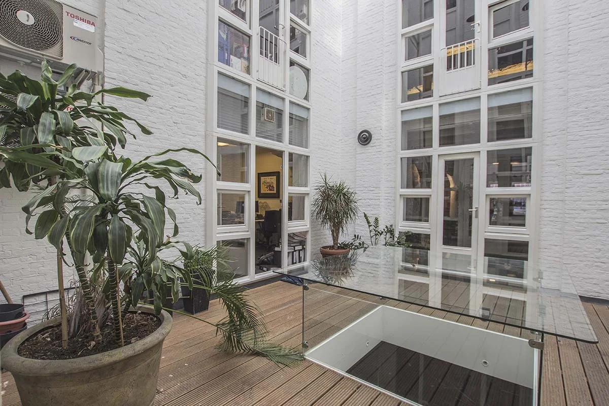 Moderne kantoorruimte met glazen dak en planten aan de Korte Leidsedwarsstraat in Amsterdam.