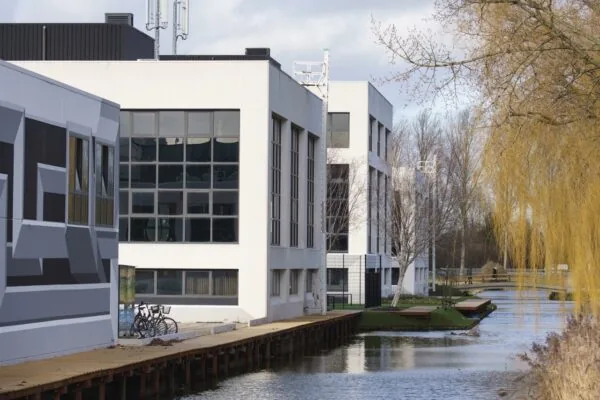Moderne kantoorgebouwen aan het water aan de Rietbaan 2-12 in Capelle aan den IJssel, omgeven door bomen en een houten wandelpad.