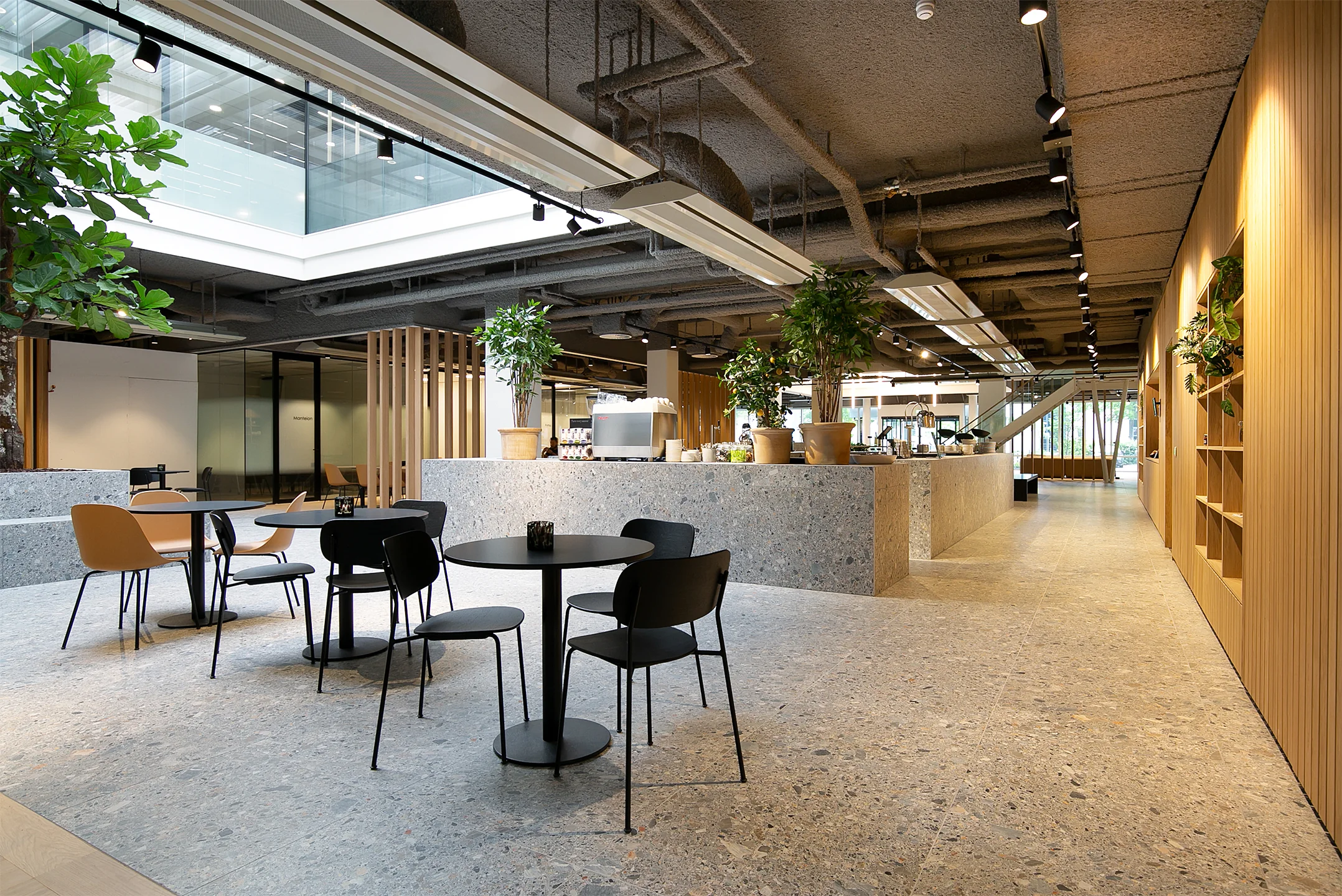 Moderne en open kantoorruimte aan de Rijnzathe 6 in De Meern met zitgelegenheid, grote planten en een koffiebar.