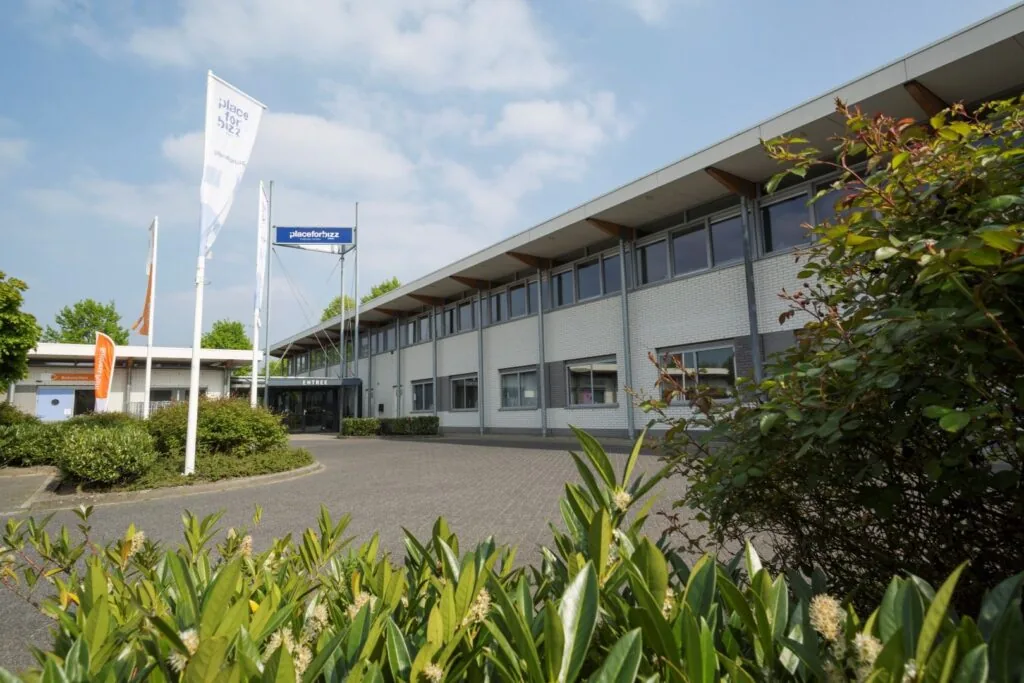 Vooraanzicht van het kantoorpand aan de Steenovenweg 5 met Place for Bizz vlaggen en entree.