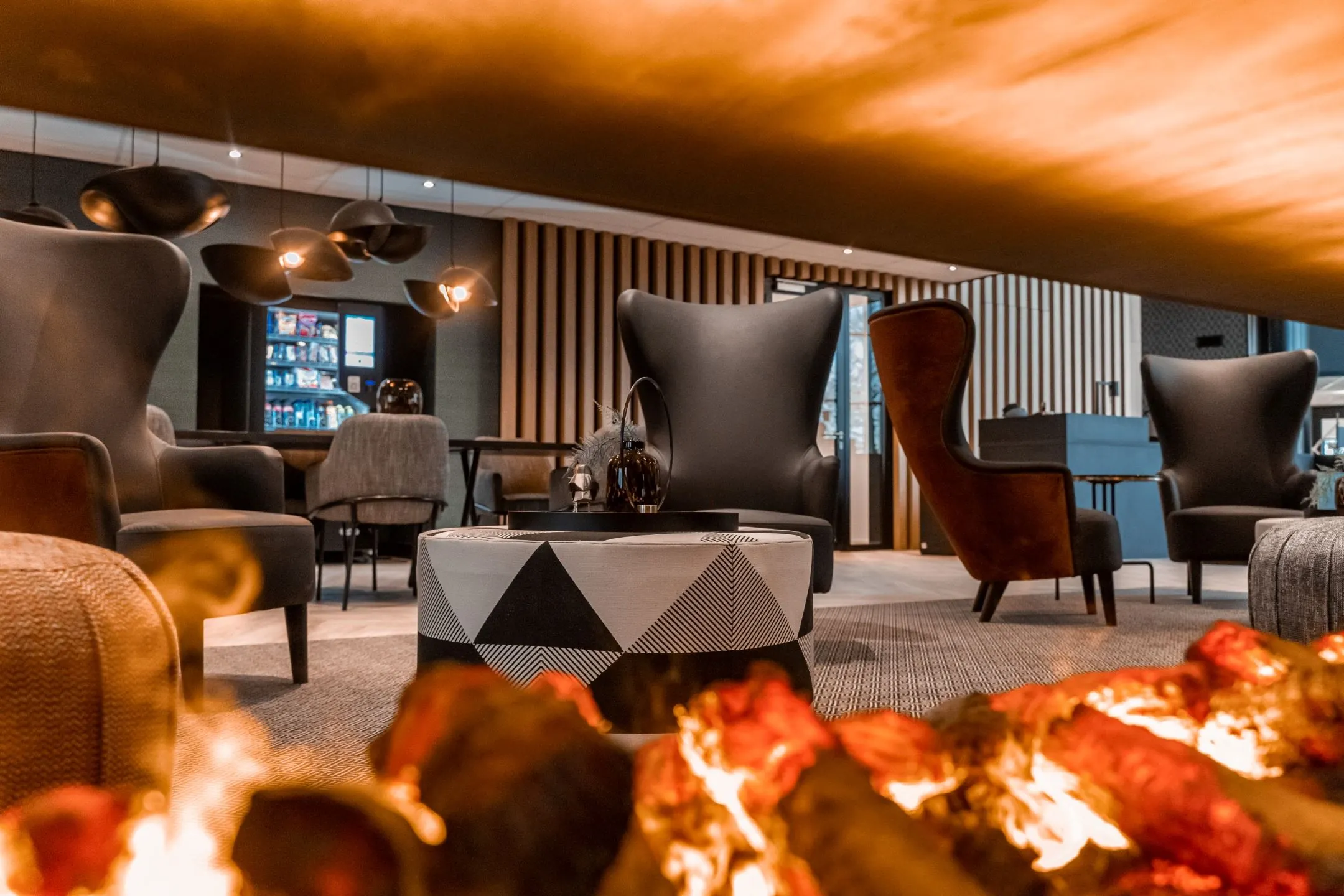 Moderne en sfeervolle loungehoek met designmeubilair en haardvuur in een kantoorruimte aan de Reitscheweg 1.