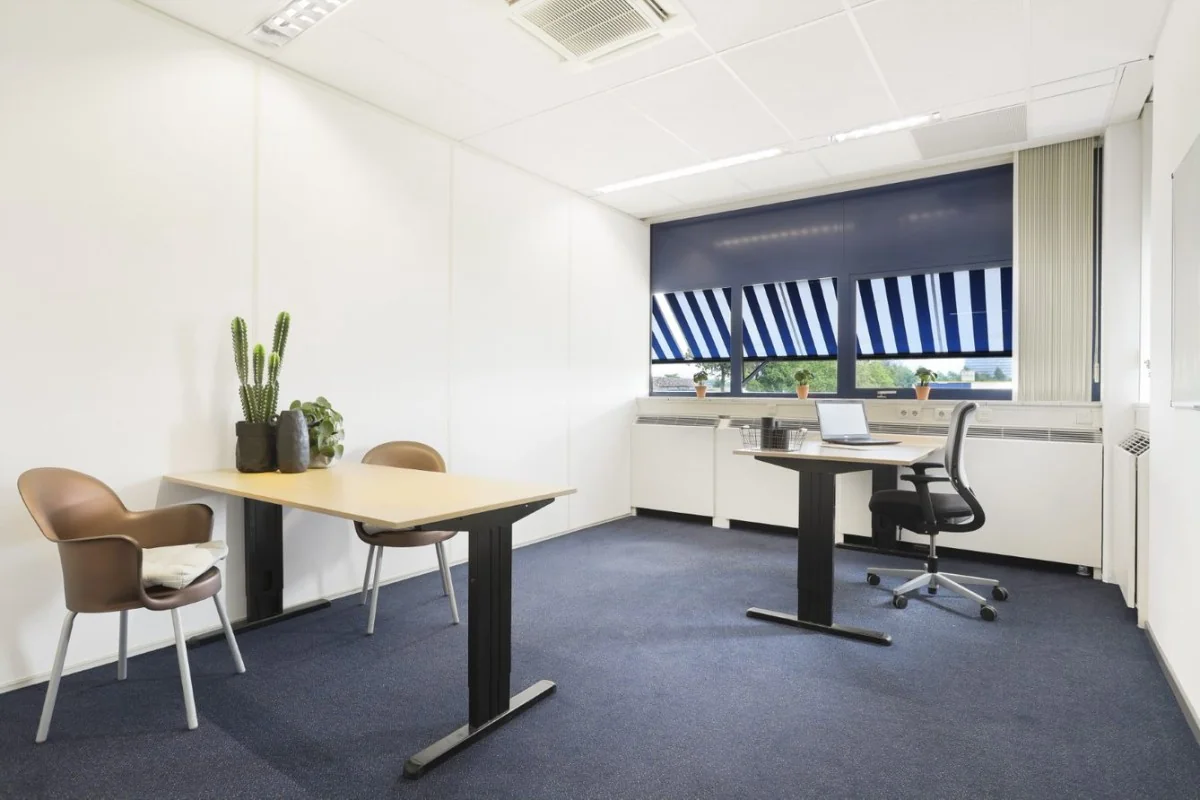 Moderne, lichte kantooruimte in Markerkant Almere met twee bureaus, kamerplanten en uitzicht op blauwe zonwering.