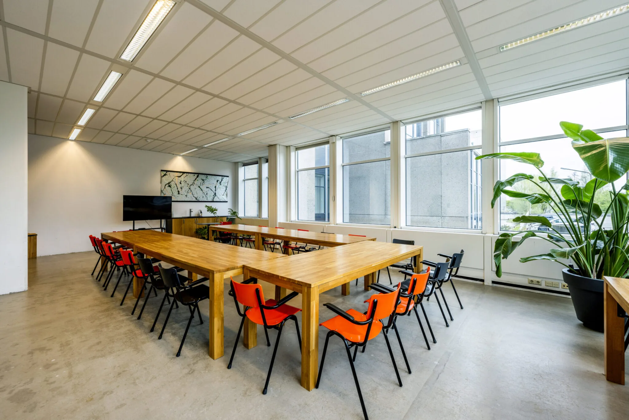 Vergaderruimte Kronenburg 020 ontworpen door Paul Starink met houten tafels, rood-zwarte stoelen en grote ramen met veel lichtinval.