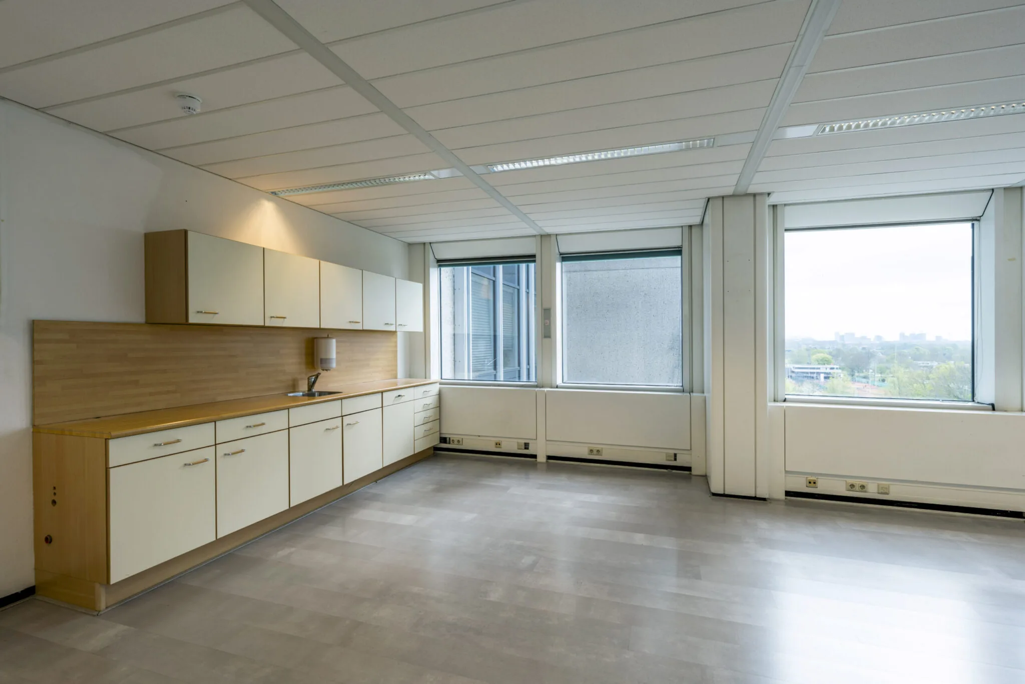 Ruime, lichte pantry met ingebouwde keukenkasten en uitzicht over de stad in kantoorgebouw Kronenburg.