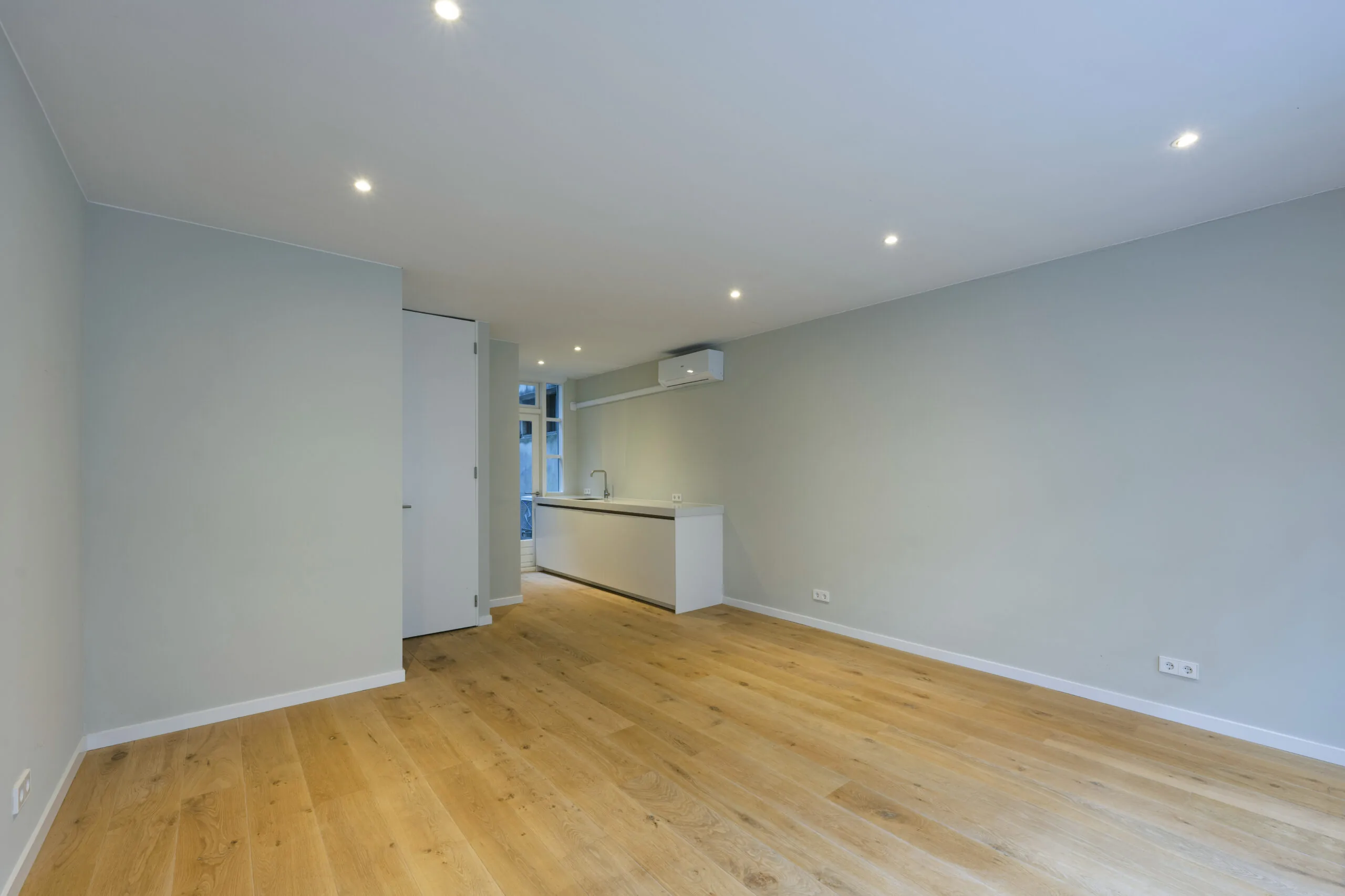 Modern ingerichte, lege woonkamer met houten vloer en open keuken aan de Leliestraat.