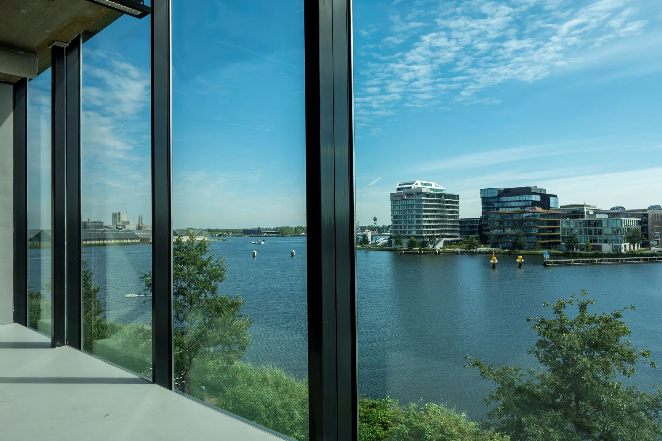 Uitzicht vanuit een modern kantoorgebouw aan de Moermanskkade op het water en omliggende kantoren aan de overzijde.