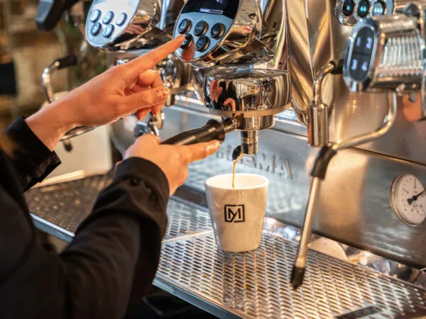Een persoon bereidt een kop koffie met een espressomachine.