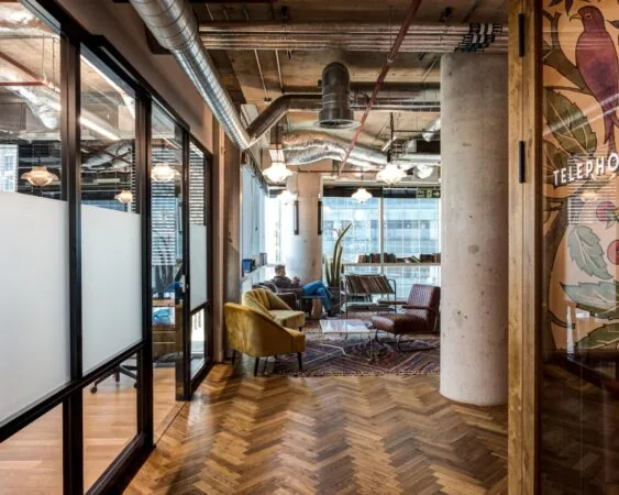 Moderne loungewerkruimte aan de Spuistraat 111 met industrieel interieur, houten visgraatvloer en comfortabele zitplekken.