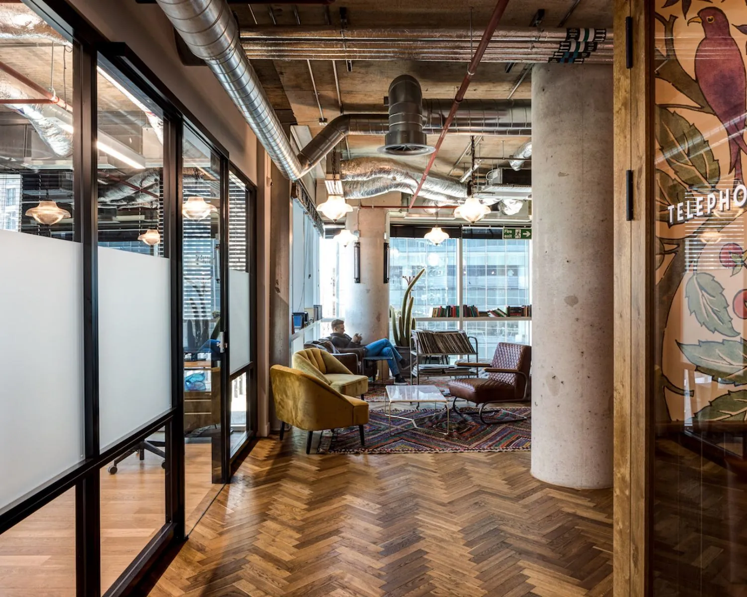 Moderne loungewerkruimte aan de Spuistraat 111 met industrieel interieur, houten visgraatvloer en comfortabele zitplekken.