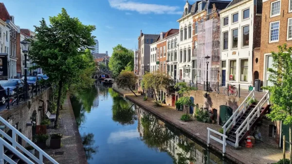 Canal view in Utrecht-Oost with historic buildings, trees, and reflections in the water on a sunny day.