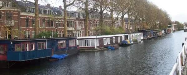Houseboats lined up along a canal with traditional brick houses in the Utrecht-West neighborhood.
