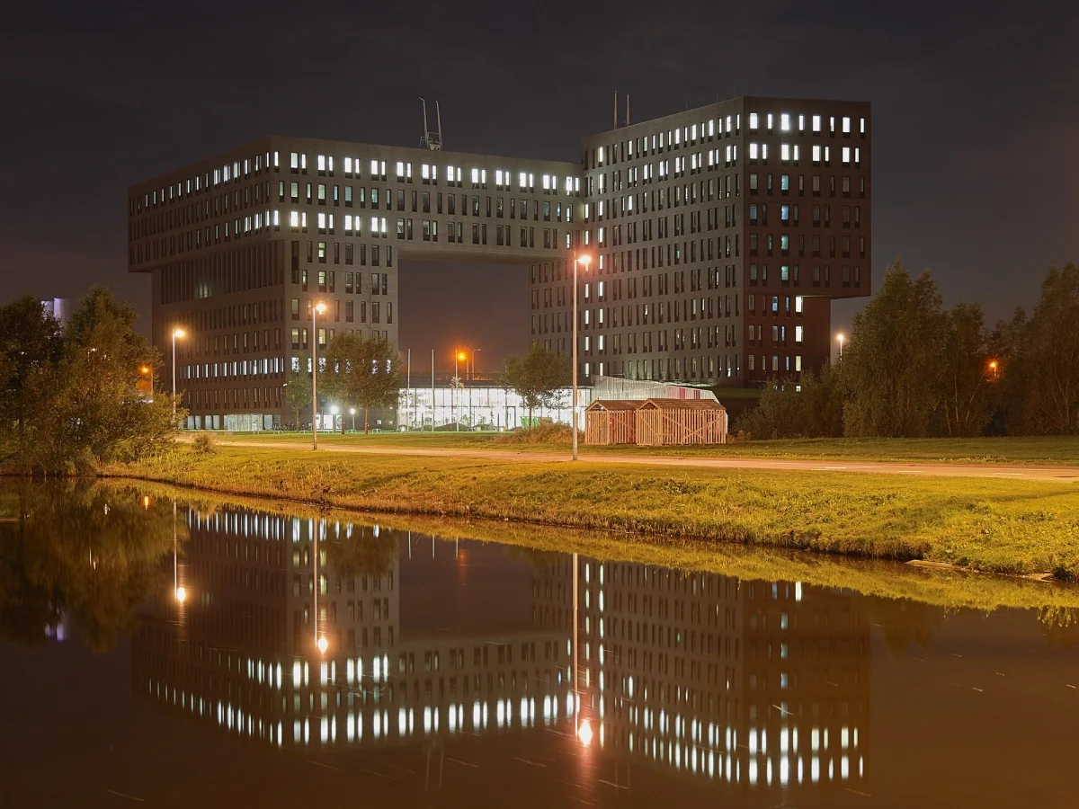 Kantoorgebouw aan de Van Deventerlaan 31-51 te Utrecht, 's avonds verlicht en weerspiegeld in het water op de voorgrond.