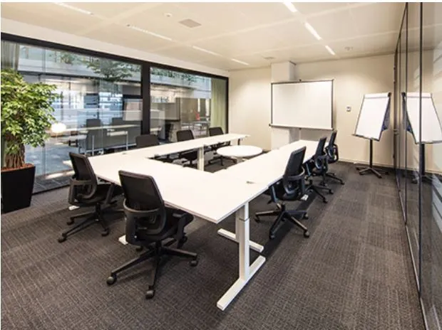 Een moderne vergaderzaal met een U-vormige tafelopstelling, stoelen, een whiteboard en flipovers.