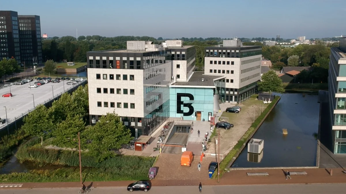 Luchtfoto van het kantoorgebouw aan het John M. Keynesplein in Amsterdam met de opvallende glazen entree en grote 'B' op de gevel.