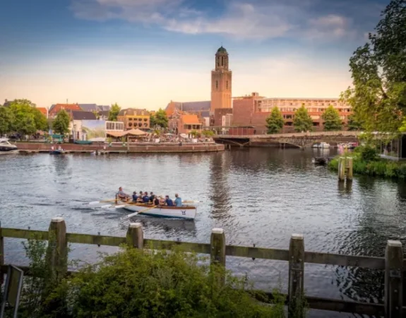 A rowing boat glides along a canal in Zwolle with the Peperbus tower visible in the background.
